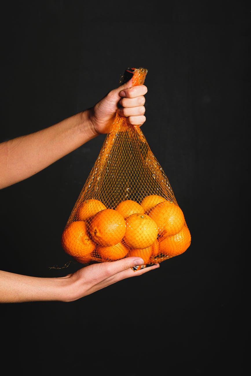 a fresh orange inside of a fruit net