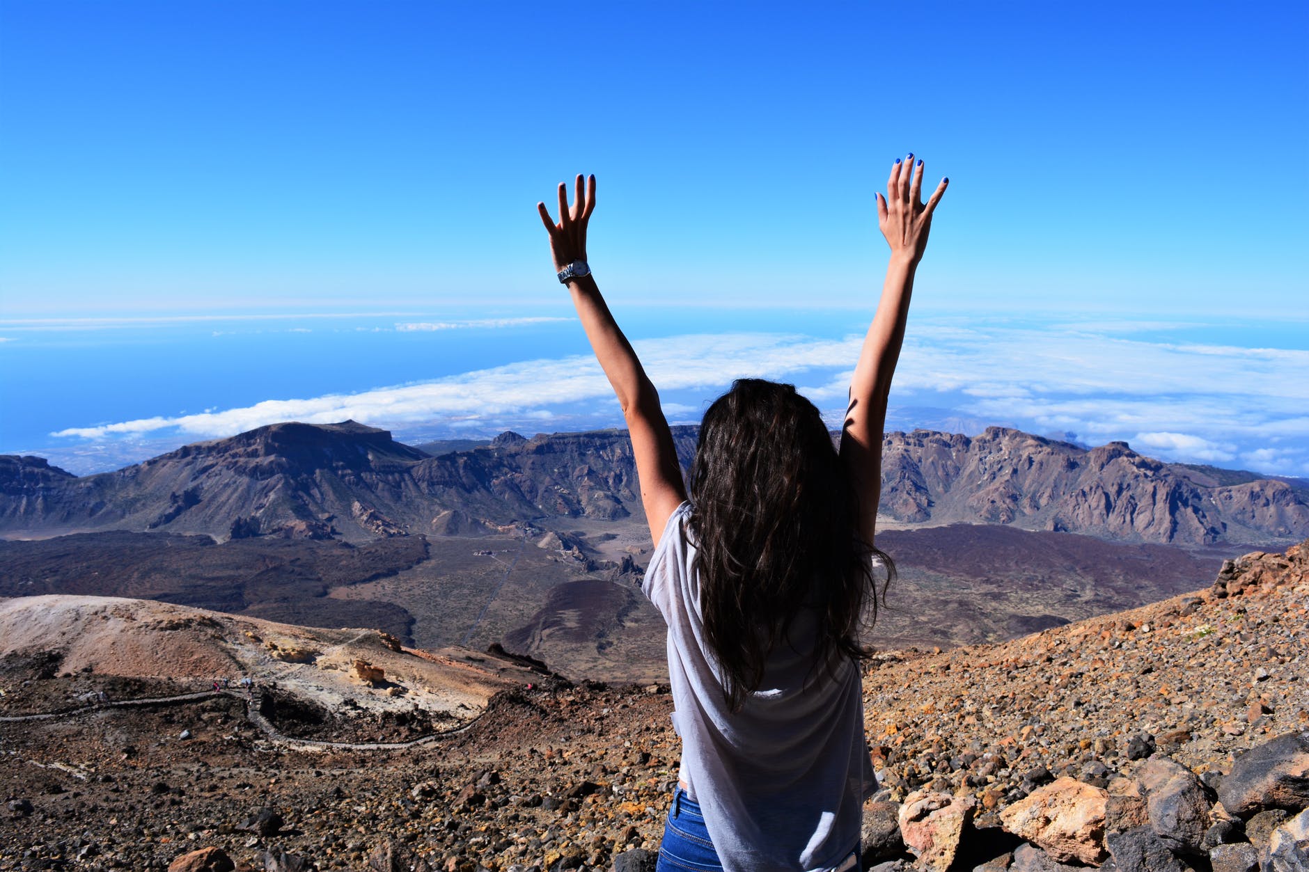 woman standing on mountain while raising her hands